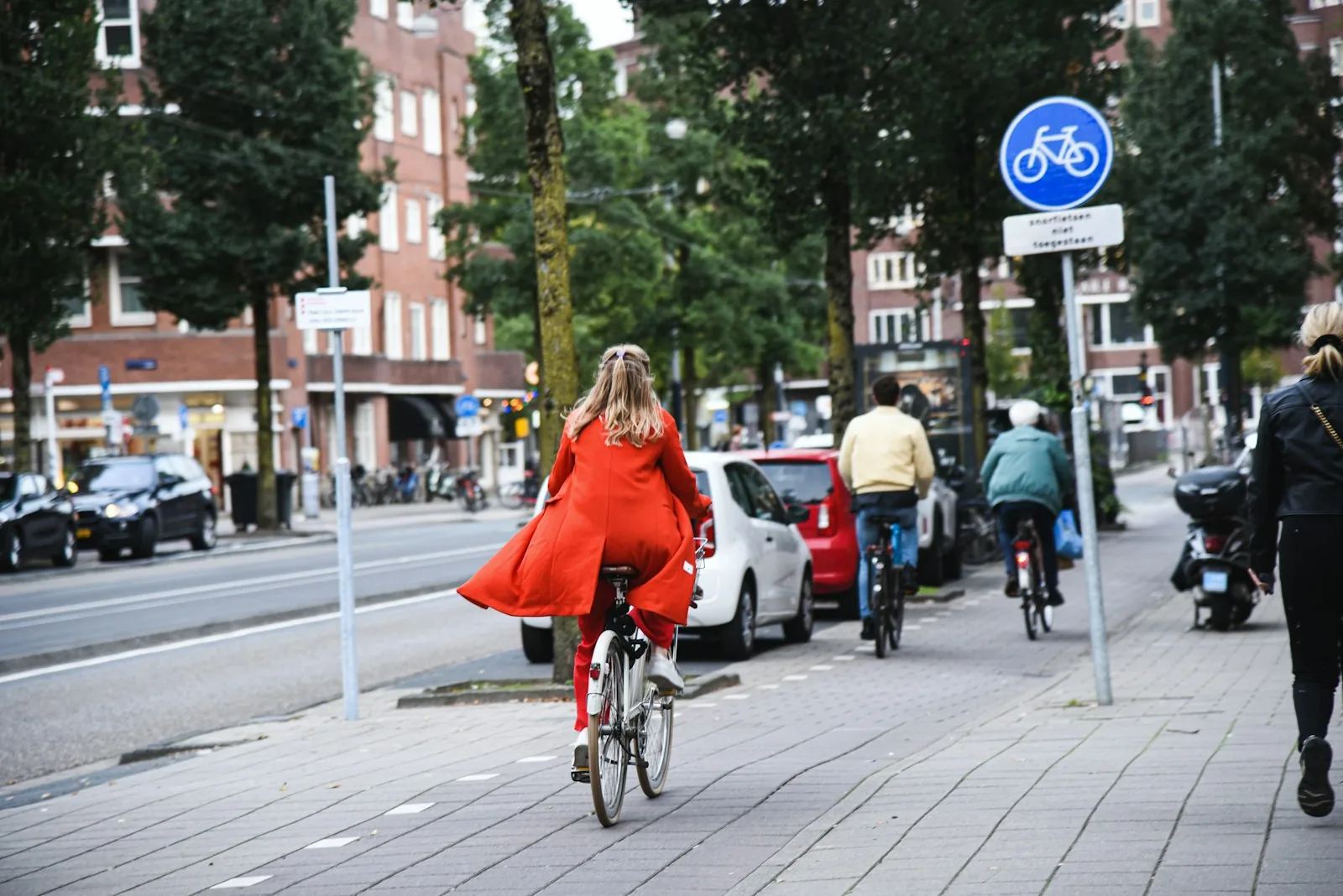 Una calle viva de una ciudad con una ciclista, peatones y carril bici